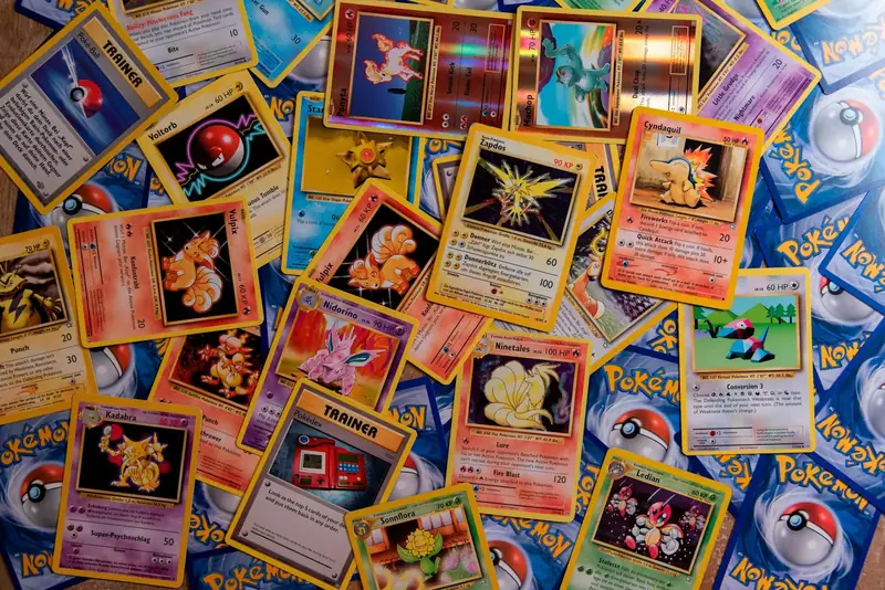 Dozens of Pokemon cards spread face up across a wooden table, commons and holos mixed together